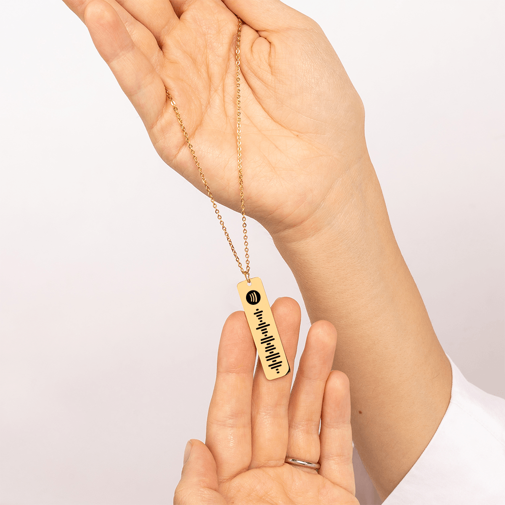 Image shows woman holding up the custom Spotify necklace in gold.